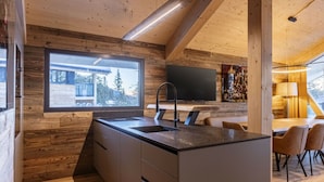 A modern kitchen with a large window, wooden walls, and a flat-screen TV. - Superior Chalet #4 With Sauna & Hot Tub (Stadl-Predlitz)