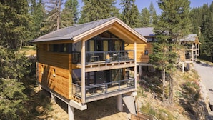 A two-story wooden cabin with a balcony, surrounded by trees. - Superior Chalet #4 With Sauna & Hot Tub (Stadl-Predlitz)