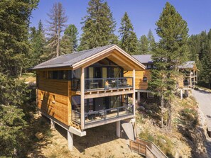 A two-story wooden cabin with a balcony, surrounded by trees. - Superior Chalet #4 With Sauna & Hot Tub (Stadl-Predlitz)