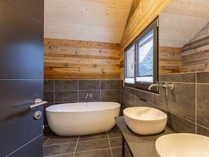 A modern bathroom with a freestanding bathtub, a vessel sink, and a window providing natural light. - Superior Chalet #4 With Sauna & Hot Tub (Stadl-Predlitz)