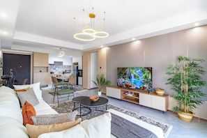 A modern living room with a sofa, coffee table, and a TV on a stand. - Luxury 4BR All-ensuite Heated Pool Riverside, Nairobi (Nairobi)