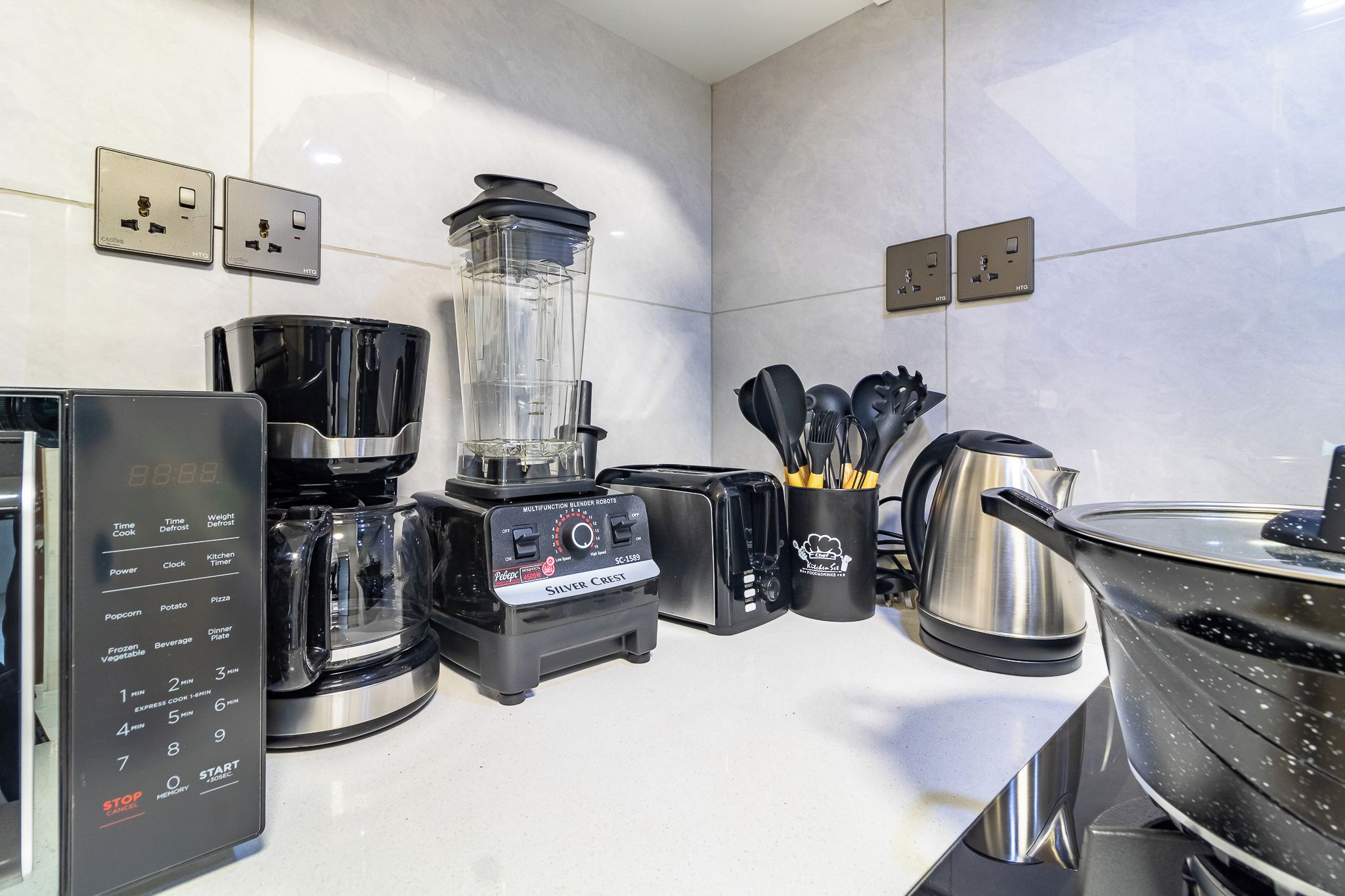 A modern kitchen with a coffee maker, blender, toaster, and kettle.