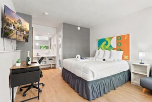A hotel room with a bed, desk, chair, TV, and artwork. - Hotel-Style Room Pool, Disney Shuttle (Kissimmee)