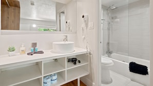 A modern bathroom with a white sink, mirror, and glass shower enclosure. - Hotel-Style Room Pool, Disney Shuttle (Kissimmee)