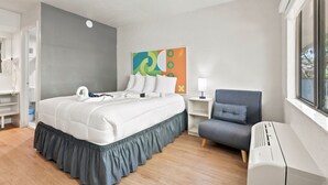A hotel room with a bed, a chair, a bedside table, a lamp, and a window. - Hotel-Style Room Pool, Disney Shuttle (Kissimmee)