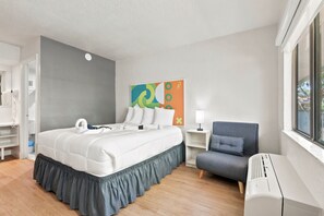 A hotel room with a bed, a chair, a bedside table, a lamp, and a window. - Hotel-Style Room Pool, Disney Shuttle (Kissimmee)