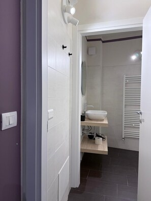 A modern bathroom with a white sink, mirror, and towel rack. - Ametista | Urban Suite (Valenza)