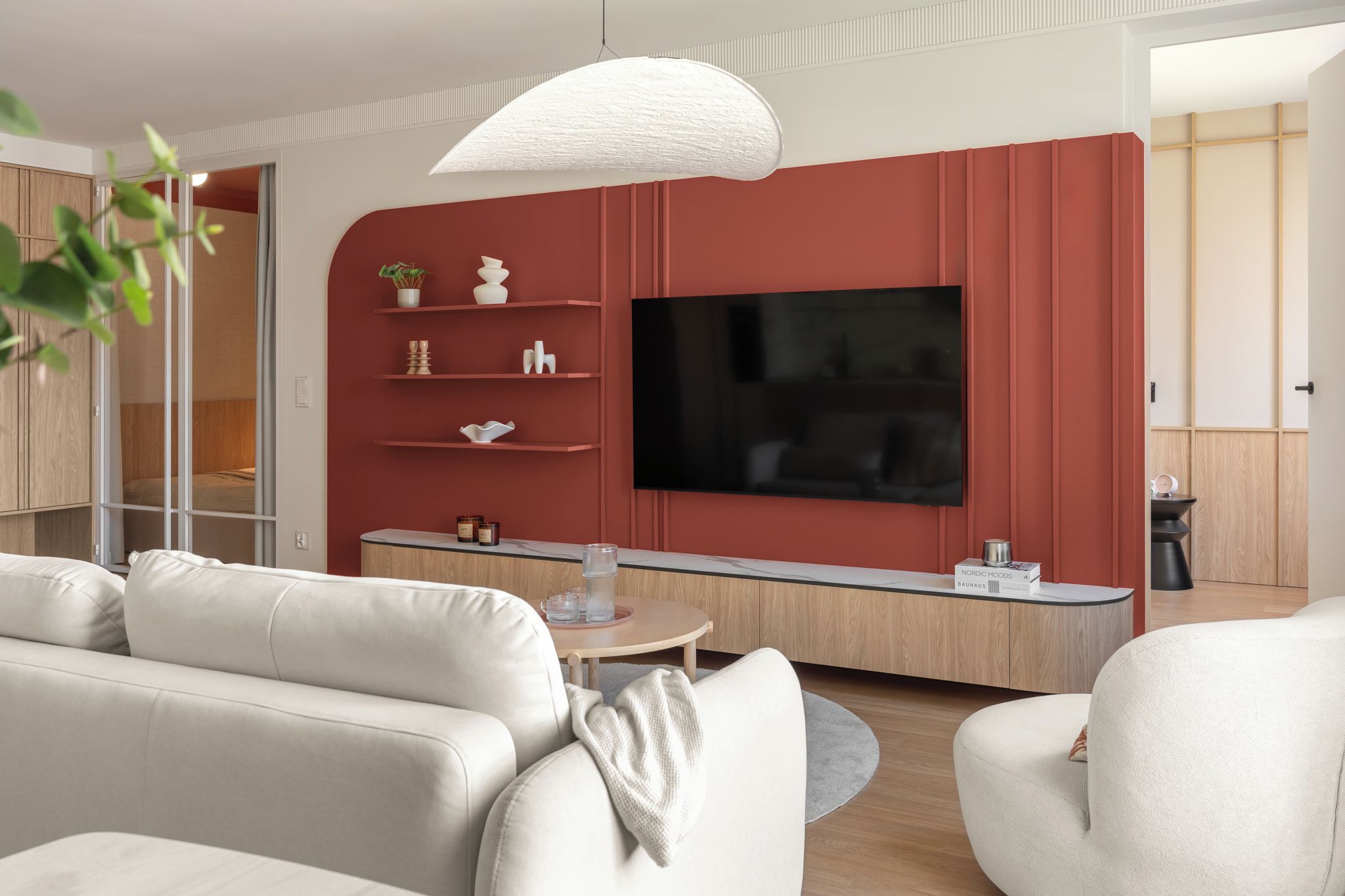 A modern living room with a flat-screen TV, a sofa, a coffee table, and a pendant light.