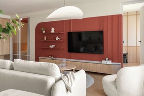 Una sala de estar moderna con un televisor de pantalla plana, un sofá, una mesa de centro e iluminación colgante.