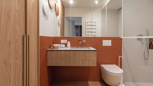 A modern bathroom with a wooden vanity, a toilet, and a shower area. - Wilcza Premium Residence with parking (Gdańsk)