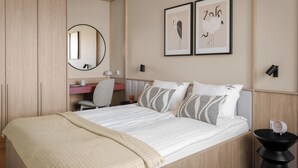 A bedroom with a bed, a desk, a chair, a mirror, and two framed pictures on the wall. - Wilcza Premium Residence with parking (Gdańsk)