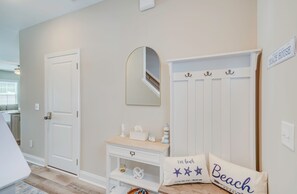 A hallway with a white door, a mirror, a small console table with decorative items, and a sign that reads 'Welcome to the Beach House.' - Spacious 3-bedroom townhome in beautiful Cedar Point, NC (Cedar Point)