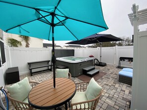 A patio with a hot tub, a table with chairs, and a large umbrella. - Spacious 3-bedroom townhome in beautiful Cedar Point, NC (Cedar Point)