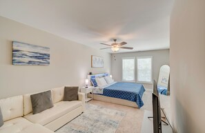 A bedroom with a bed, a nightstand, a ceiling fan, a window with blinds, a wall-mounted artwork, and a television. - Spacious 3-bedroom townhome in beautiful Cedar Point, NC (Cedar Point)