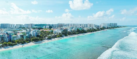 Un paisaje urbano costero con una playa, aguas turquesas cristalinas y edificios altos.