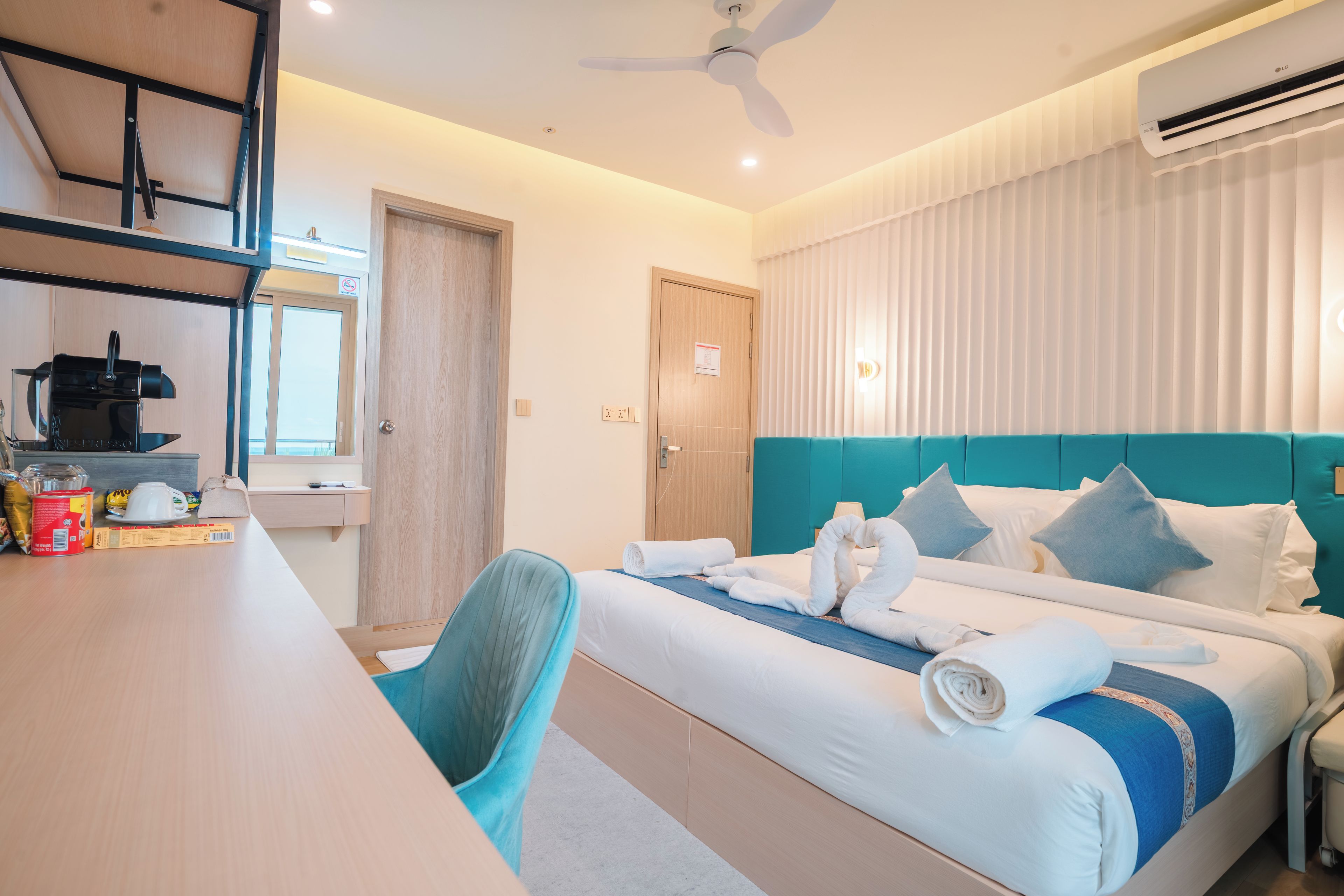 A hotel room with a bed, a desk, a chair, and an air conditioner.