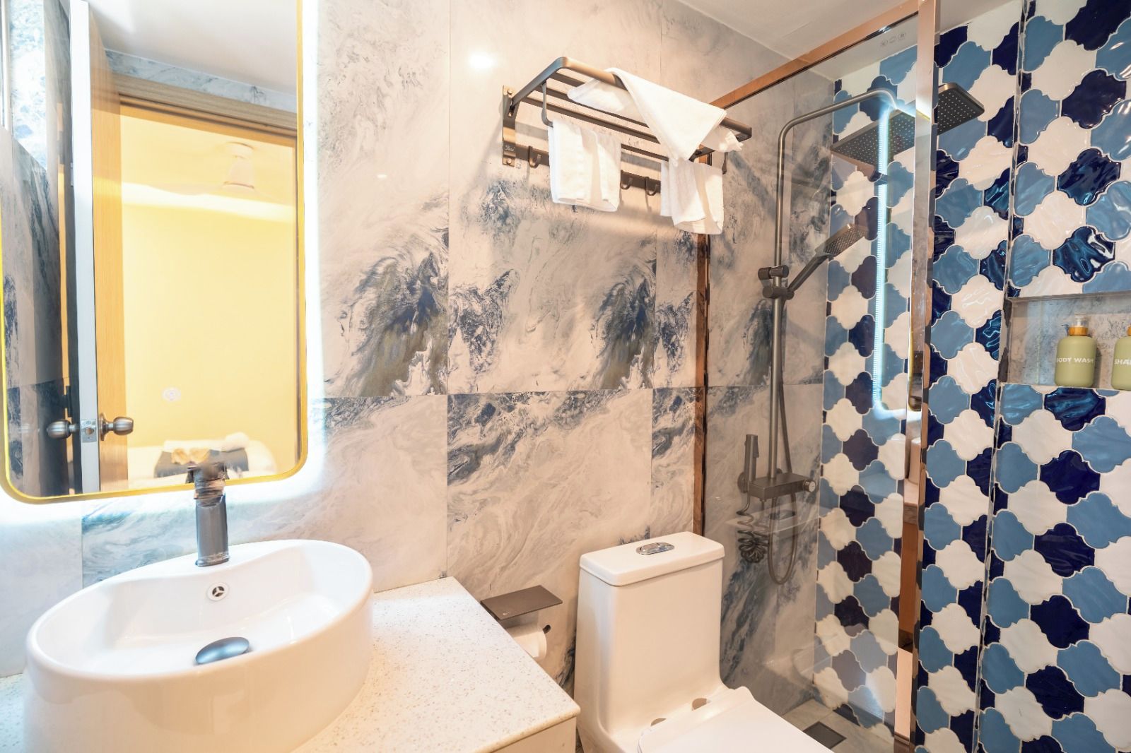 A bathroom with a marble sink, a toilet, a shower with a glass door, and a towel rack.