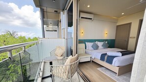 A balcony with a glass table and chairs, a bed with a blue headboard, and an air conditioning unit. - Six Palms Beach (Male)