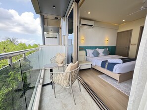 A balcony with a glass table and chairs, a bed with a blue headboard, and an air conditioning unit. - Six Palms Beach (Male)