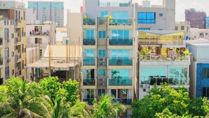 A multi-story building with balconies, large windows, and a construction site on the ground floor. - Six Palms Beach (Hulhumale)