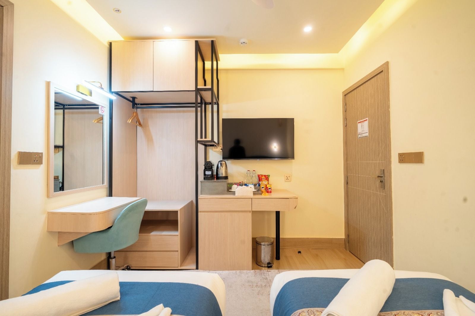 Habitación de hotel pequeña con cama, escritorio, espejo, televisor y armario.