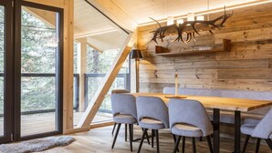 Een moderne eetruimte met een houten plafond, een lange tafel en grijze stoelen.