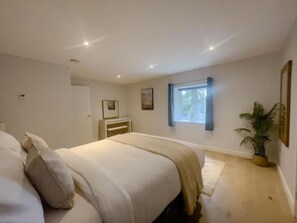 A bedroom with a bed, a window, a plant, and a door. - The Gatehouse & Lodge | Large Group Retreat (Holt)