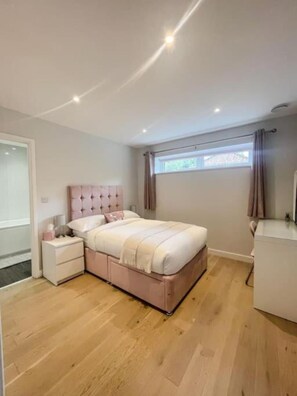 A bedroom with a bed, nightstands, a dresser, and a window with curtains. - The Gatehouse & Lodge | Large Group Retreat (Holt)