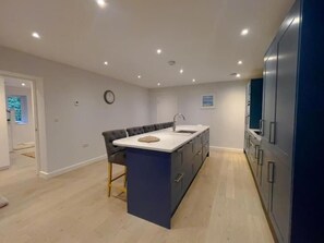 Une cuisine moderne dotée d’un îlot central, d’un coin repas et de meubles de rangement intégrés.