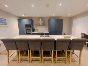 Una cucina moderna con isola centrale, elettrodomestici integrati e zona pranzo con sei sedie.