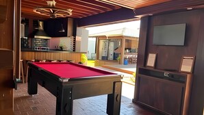 A billiards table in a room with a wooden ceiling and a television mounted on the wall. - Recanto Reino Encantado 1 (Olímpia)
