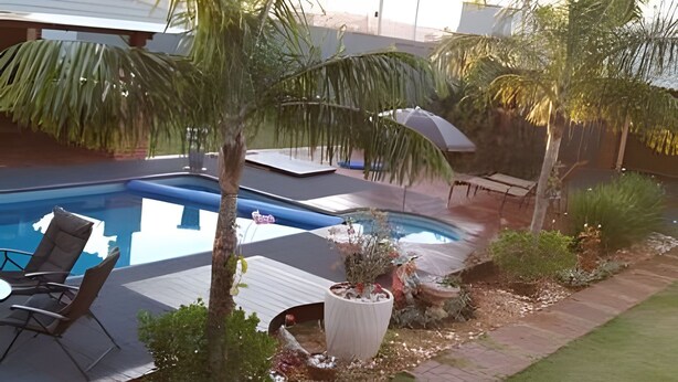 A swimming pool with lounge chairs, a palm tree, and a small garden area. - Recanto Reino Encantado 1 (Olímpia)