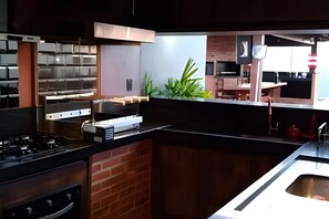 A modern kitchen with a gas stove, stainless steel appliances, and a brick backsplash. - Recanto Reino Encantado 1 (Olímpia)