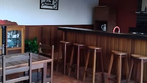 A bar area with wooden stools, a counter with a red faucet, and a framed picture on the wall. - Recanto Reino Encantado 1 (Olímpia)