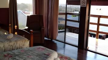 Quarto de hotel com uma cama, uma cadeira e vista para o exterior.