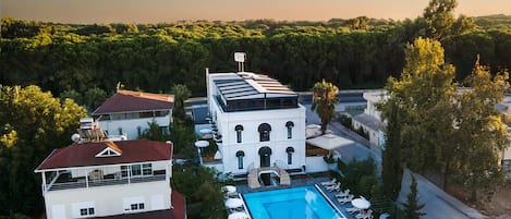A hotel with a swimming pool, a tennis court, and a large building with a balcony.