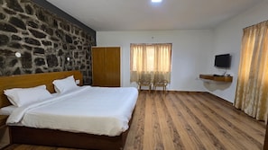 Un dormitorio con cama, armario, televisor y ventana con cortinas.