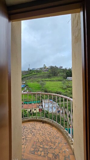 A balcony with a view of a green landscape and buildings.