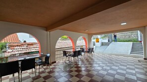 Un espacio interior amplio con piso a cuadros, una mesa con sillas y vista al exterior a través de arcos.