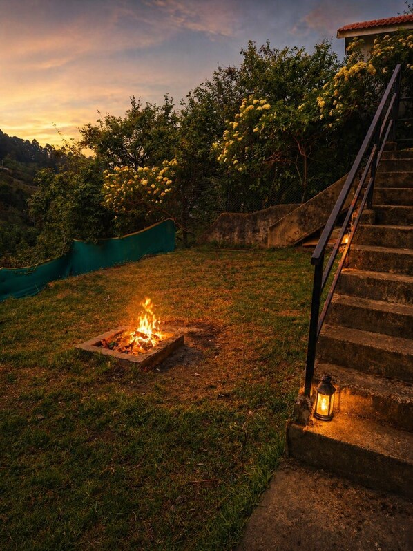 A fire pit in a grassy area with a staircase and a lantern.