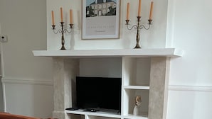 Una sala de estar con sofá, chimenea, televisor y un cuadro en la pared.
