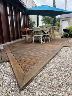 Eine Außenpatio mit einer Holzterrasse, einem Tisch und Stühlen.