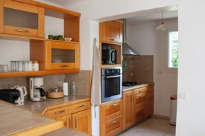Eine Küche mit Holzausstattung, einer Mikrowelle, einem Backofen und einer Kaffeemaschine.