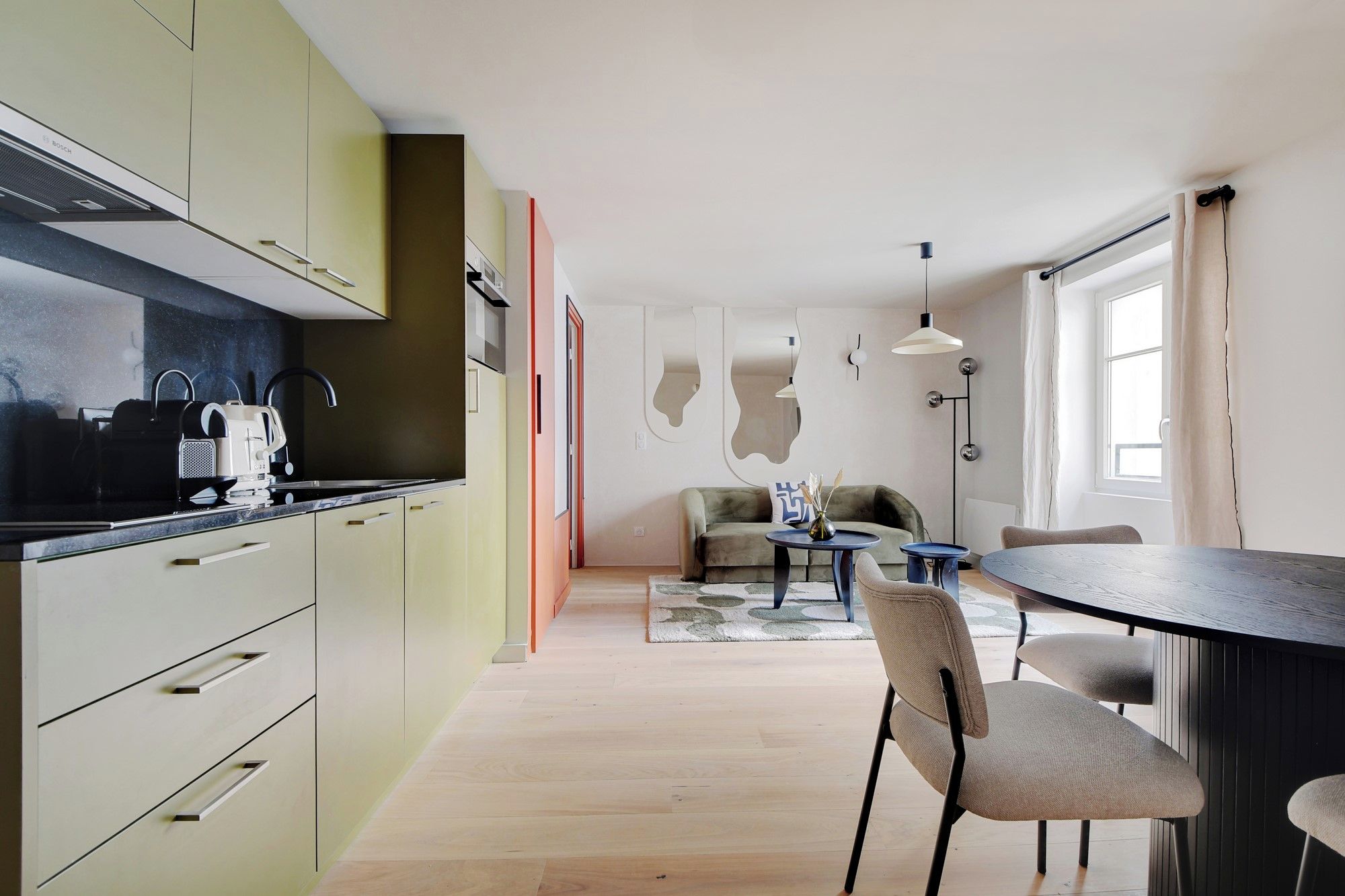 Una cocina moderna con un extractor Bosch, un comedor con una mesa redonda y sillas, y una sala de estar con un sofá y una mesita de centro.