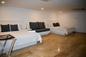 A hotel room with two beds, a small table, and a bench. - Colonial-style house in the heart of Getsemaní (Cartagena)