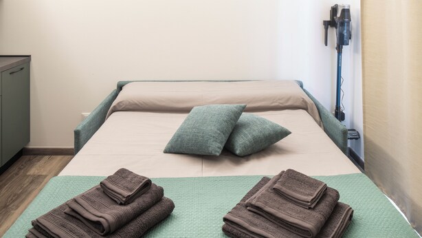 A neatly made bed with pillows and folded towels. - Borgo Il Castello, Elsa Apartment (Montichiari)