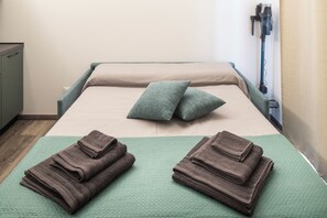Ein ordentlich bezogenes Bett mit Kissen und gefalteten Handtüchern.