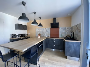 A modern kitchen with a central island, pendant lighting, and a tiled backsplash.