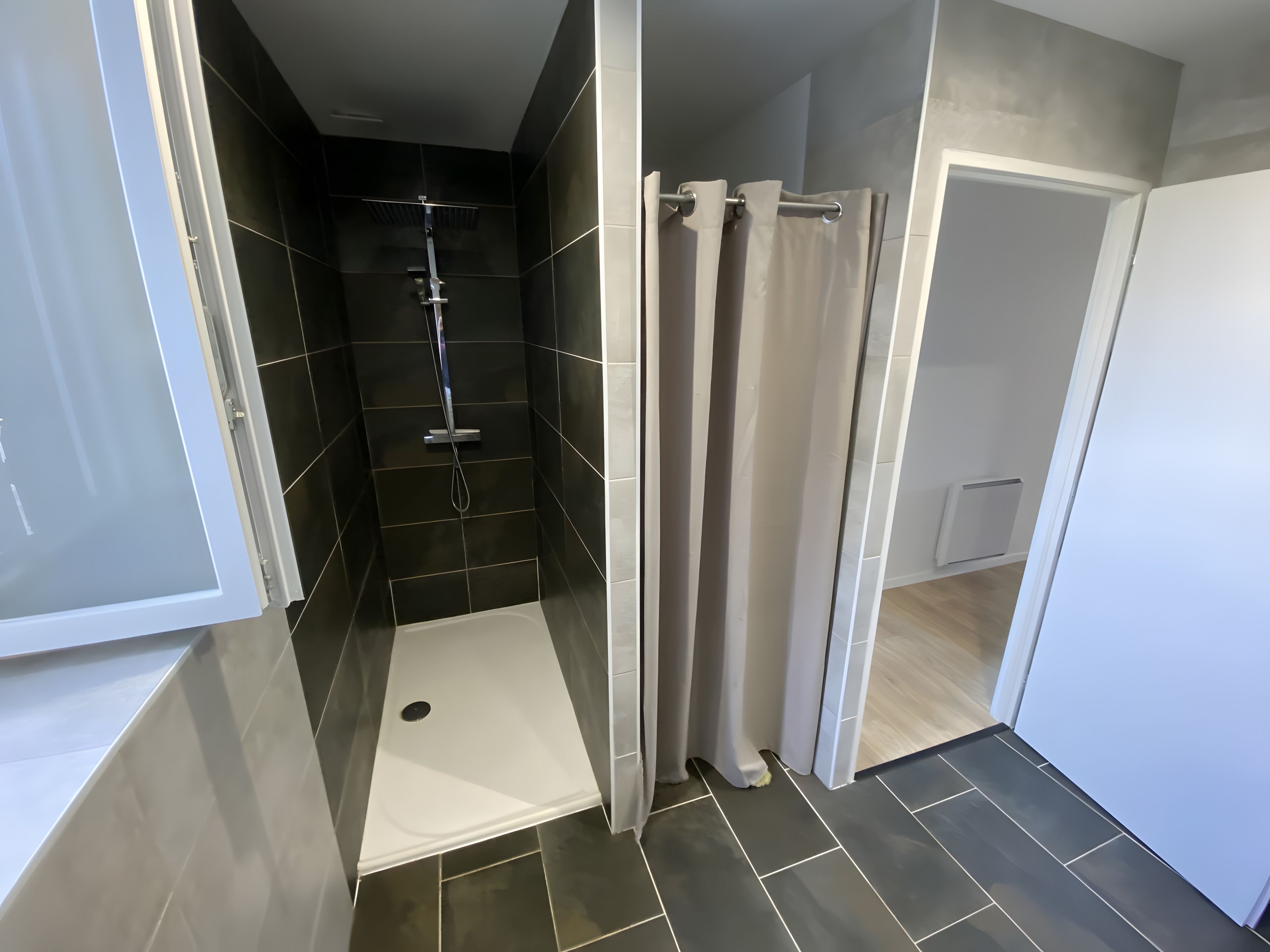 Een moderne badkamer met een douche, toilet en wastafel.