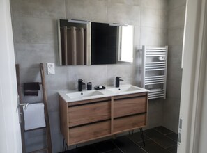 A modern bathroom with a double sink vanity, a mirror, and a towel rack.
